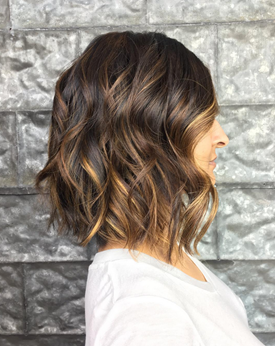 Model with brunette hair and warm caramel balayage.